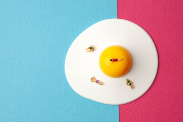 miniature people on egg with blue and pink background