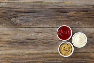 Fototapeta na wymiar Set of three kinds of classic sauces on wooden background. Mayonnaise ketchup mustard