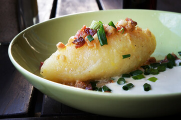 Cepelinai (zeppelin) with sour cream, cracklings and and green onion.