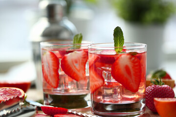 Close up of refreshing cocktail with strawberries and green mint standing on wooden desk on the kitchen