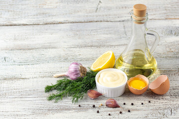 Fototapeta na wymiar Mayonnaise sauce with garlic, egg, oil, lemon and herbs on wooden background