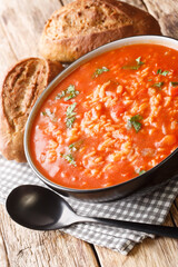 tomato rice soup served with bread close-up in a bowl on the table. vertical