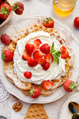 Homemade waffles with whipped cream and fresh strawberries top view