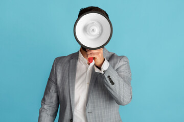 Businessman holding megaphone in front of his face on blue background