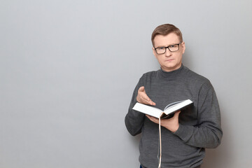 Portrait of serious man holding open big book and pointing at text