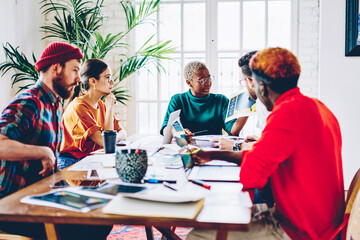 Smart african american female coach of student group checking results of research and speaking on meeting table,serious woman presenting her ideas to multiracial crew of colleagues explain strategy.