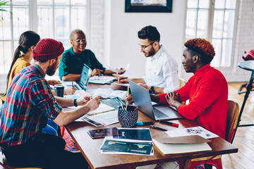 Multiracial crew of professional employees sitting at desktop discussing ideas and strategies for startup statement, skilled african american woman coach making workshop with creative students.