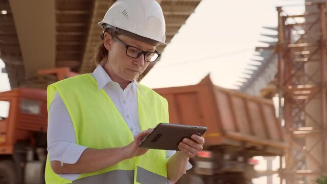 Woman foreman working on construction site using tablet.
