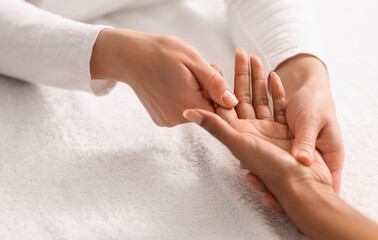 Cropped of masseuse making hand massage for african lady