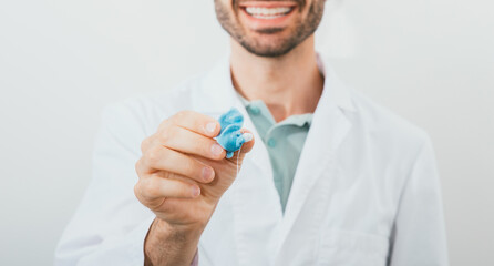 Positive audiologist holding in his hands molded individual hearing aid earmolds for his patient,...