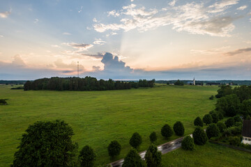 Fototapeta premium Aerial view of amazing sunset at summer season. Nature landscape. Landscape surrounded by green fields, rivers and trees.