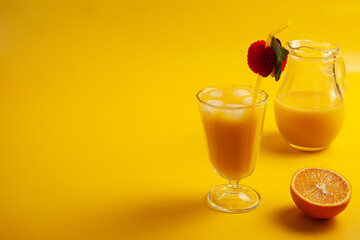 Glass with orange juice with gkass jar and orange half closeup.on yellow background.