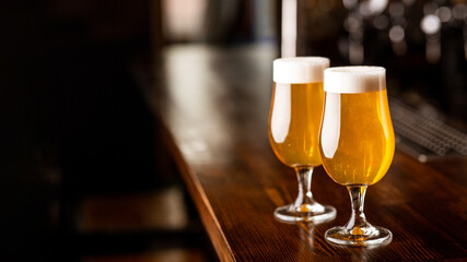 Evening at pub. Glasses with beer and foam on wooden brown bar counter in pub