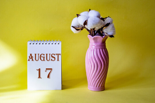 Calendar with text 17 august on yellow background and with a vase of flowers
