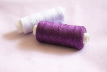 white and purple sewing threads lie on the fabric