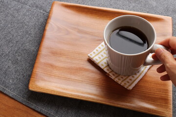 Woman's hand is touching and holding coffee cup. Coffee break with black coffee mug.
