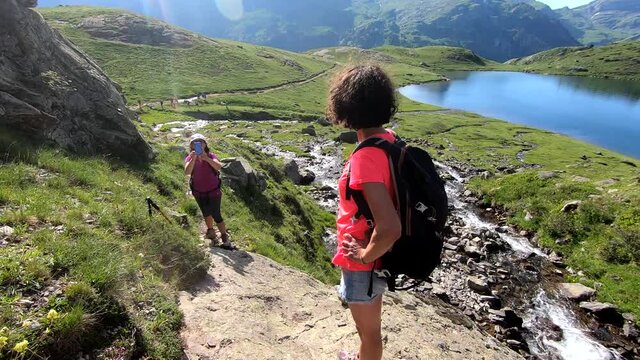 hiker women taking a picture near waterfall of Ayous, french Pyrenees