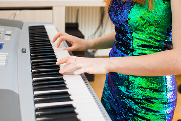 The young woman is playing in the studio on a synthesizer
