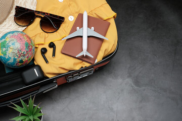 Flat lay, Vacation planing and travel on holiday concept on vintage cement table background with plane and passport, earphone and straw hat, sunglasses and orange suitcase, top view with copy space