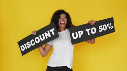 beautiful young black woman with discount up to 50% sign dancing isolated on yellow background