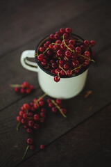 Mug overflowing with red berries on a wooden background. Berry scattered near a cup on a wooden table in the village. Flat lay

