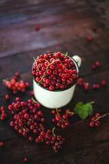 Mug overflowing with red berries on a wooden background. Berry scattered near a cup on a wooden table in the village. Flat lay
