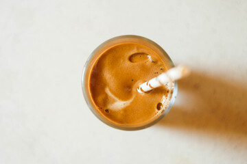 Dalgona coffee in glass with paper straw banner. Trending drink on paper background. Cold cocktail. Whipped coffee cream