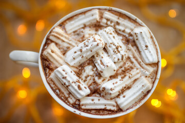 Cup of coffee with marshmallow surrounded by christmas lights