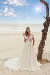 Fototapeta na wymiar Beautiful bride in her wedding dress posing for photos on the beach.