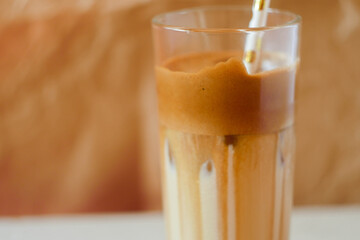 Dalgona coffee in glass with paper straw banner. Trending drink on paper background. Cold cocktail. Whipped coffee cream