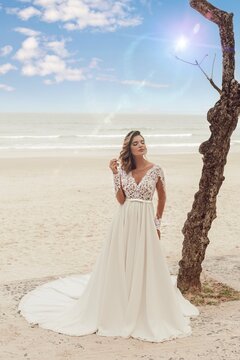Beautiful bride in her wedding dress posing for photos on the beach.
