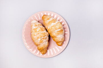 Two Fresh and Tasty Croissants on a Pink Plate Blue Background Top View Horizontal