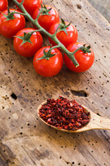 Cherry tomato branch and wooden spoon filled with dried tomato seasoning