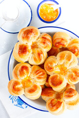 Beautiful yeast buns in the shape of flowers in an enameled bowl, top view, selective focus