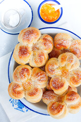 Beautiful yeast buns in the shape of flowers in an enameled bowl, top view, selective focus