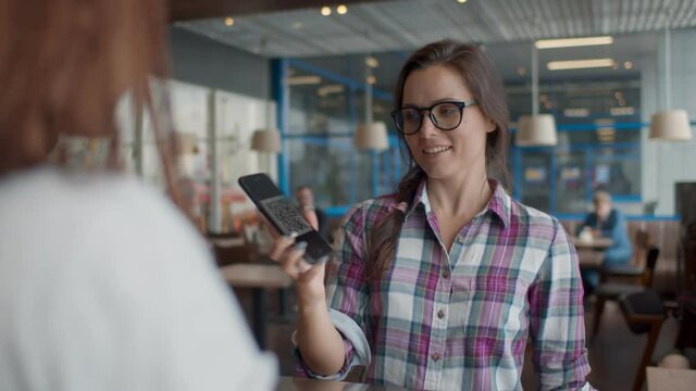 Barista scanning QR code in customer smartphone at counter in cafeteria.