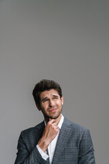 Photo of perplexed young businessman posing and looking upward