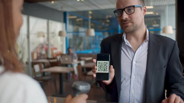 Businessman pay by scanning QR code on smartphone in coffee shop