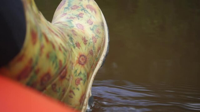 River rafting in summer. Packrafting in wilderness. A leg in a rubber boot overboard. Derzha River, Tver Region, Russia.