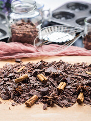 Shredded chocolate with cinnamon on wooden board and other ingredients and tools for baking