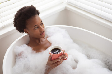 Woman with coffee cup in a bathtub