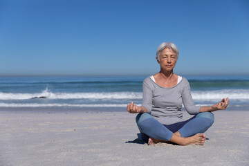 Fototapeta na wymiar Senior Caucasian woman meditating at the beach.
