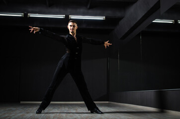 Fototapeta na wymiar A handsome guy is dancing. Ballroom dancer. The guy is dancing on a dark background. Charisma. The nature of dance. Portrait of a charismatic guy.