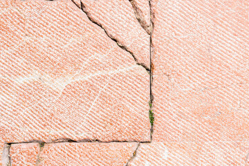 Road red tile with cracks and sprouted grass