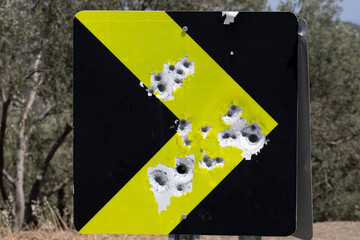 Red road traffic sign full of bullet holes. Close up.
