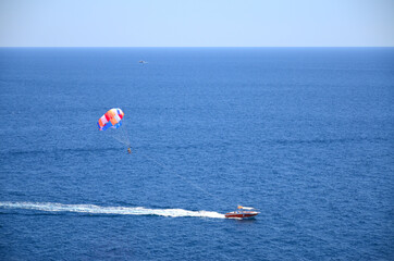 見渡す限りの青い海でモーターボートに引かれるパラセイリング