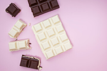 White and black chocolate bars and pieces on pink background, top view