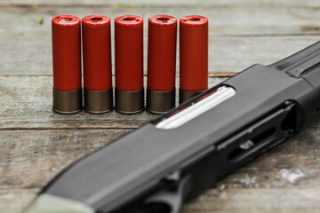 Red shotgun shells ammunition with shotgun rifle on wooden table - obrazy, fototapety, plakaty
