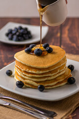 Morning Pancakes pouring maple syrup on top vertical