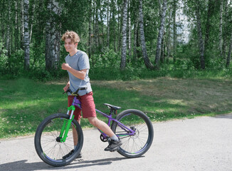 Naklejka premium happy smiling teenager boy on a bicycle. summer activity and outdoors activity concept. healthy lifestyle. teenagers leisure. BMX rider guy.